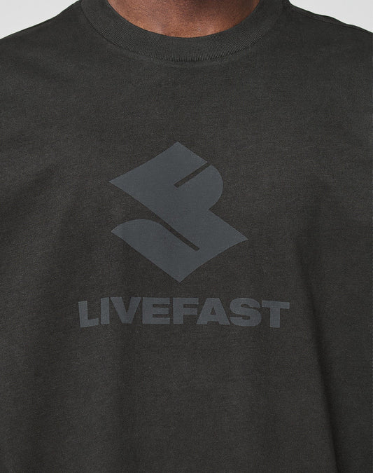 Close-up of a person wearing the Live Fast LF Tee by LIVE FAST DIE YOUNG, a black oversized shirt with a bold stylized frontprint logo and LIVEFAST in large capitals on the chest, crafted from 100% Baumwolle for ultimate comfort.