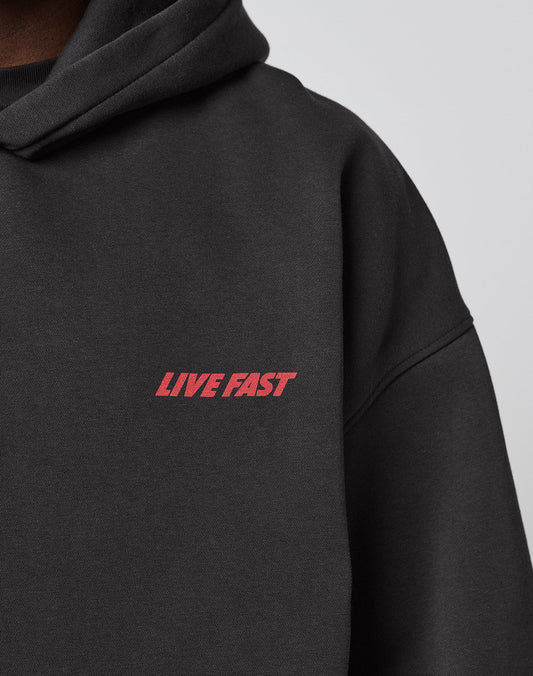 A close-up of the LFDY Globe Hooded by LIVE FAST DIE YOUNG, a black hoodie with LIVE FAST in bold red on the chest. Made from cotton-polyester blend, it features an Oversize Fit for superior comfort.