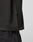 Close-up of a person wearing the Live Fast LF Tee by LIVE FAST DIE YOUNG, an oversized black shirt with black pants. A small fabric tag is attached near the hem. The background is plain and light-colored.