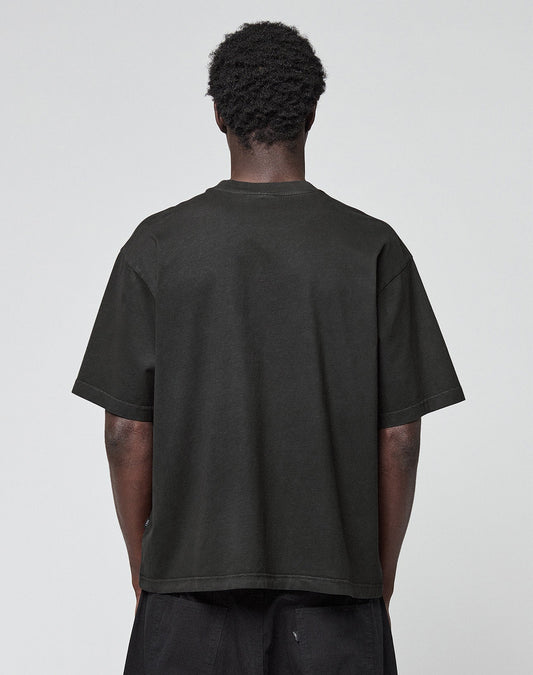 A person with short curly hair stands with their back to the camera, wearing the LIVE FAST DIE YOUNG Live Fast LF Tee in black and matching black pants against a plain light gray background.