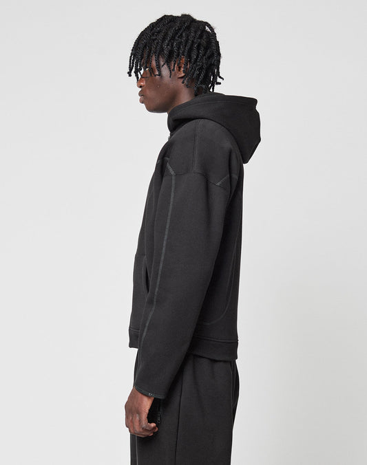 A person with short, twisted hair stands in profile, wearing the LIVE FAST DIE YOUNG LFDY Active Fleece Hooded Zip and black cotton pants, set against a plain white background.