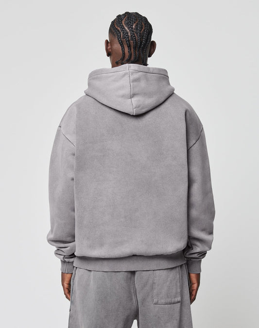 A person with braided hair is seen from behind, wearing the LIVE FAST DIE YOUNG Basic Blank Hooded and matching sweatpants in light gray cotton, styled as an oversized fit against a plain white background.