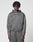 A person with medium-length curly hair wears the LFDY Active Fleece Hooded Zip by LIVE FAST DIE YOUNG in grey Oversize Fit, paired with matching pants, standing against a plain light background and looking directly at the camera with a neutral expression.