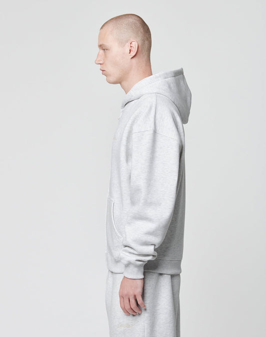 A person with a shaved head models the LIVE FAST DIE YOUNG Basic Script Hooded Zip and matching sweatpants in light gray Baumwolle-Polyester, standing in profile against a plain white background.