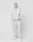 A person stands against a white background, wearing the LIVE FAST DIE YOUNG Basic Script Hooded Zip and matching sweatpants in light gray with subtle logo embroidery, made from a soft cotton-polyester blend. Their hands are in the hoodie pockets.
