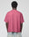 A person with short curly hair is seen from the back, wearing the oversized pink Live Fast LF Tee by LIVE FAST DIE YOUNG and light blue jeans against a plain light gray background.