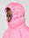 Someone wearing the Live Fast Puffer Jacket by LIVE FAST DIE YOUNG, bright pink with an oversized fit, hood up and fully zipped, looks to the side against a plain light gray background.