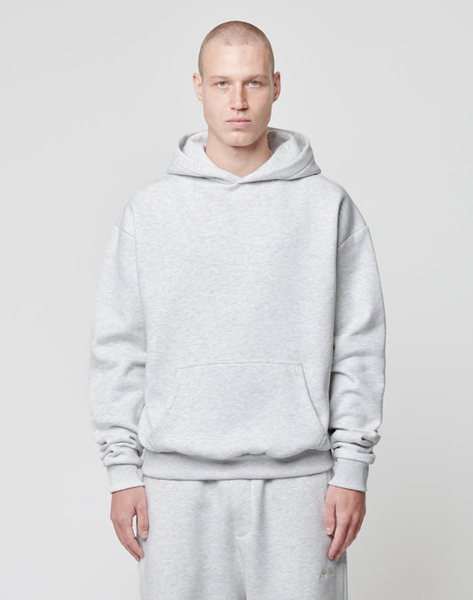 A person with a shaved head wears an oversize fit LIVE FAST DIE YOUNG Basic Blank Hooded light gray hoodie and matching sweatpants, standing facing forward against a plain light gray background.