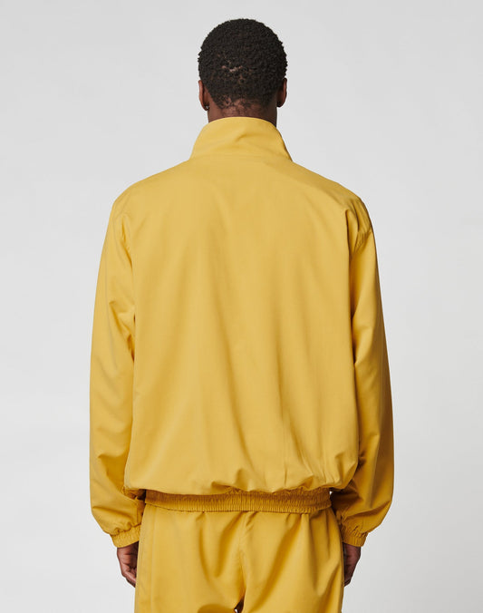 A person is seen from behind wearing an oversize-fit yellow LFDY Trackjacket and matching pants with reflective print by LIVE FAST DIE YOUNG, standing against a plain light background.