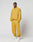 A man stands against a white background, hands in pockets, wearing LIVE FAST DIE YOUNG LFDY Trackpants—loose-fitting mustard yellow polyester with Elastikbund and reflective print—confidently looking at the camera.