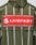 The LFDY Nylon Trackjacket by LIVE FAST DIE YOUNG is olive green with white vertical stripes, a hood with elastic drawcord, bold front and back prints including a large red patch with “LIVEFAST,” and features an oversize fit for a statement look.
