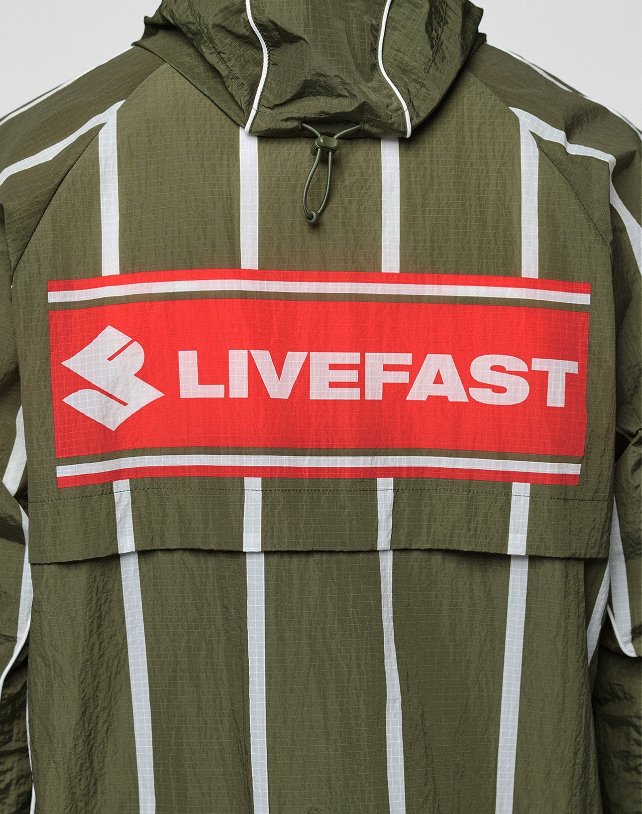 The LFDY Nylon Trackjacket by LIVE FAST DIE YOUNG is olive green with white vertical stripes, a hood with elastic drawcord, bold front and back prints including a large red patch with “LIVEFAST,” and features an oversize fit for a statement look.