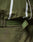 Close-up of an olive green LFDY Nylon Trackjacket by LIVE FAST DIE YOUNG, featuring crinkled fabric, white reflective stripes, Velcro strap, elastic hood drawstring, embossed patch detail, and an oversize fit for comfort.