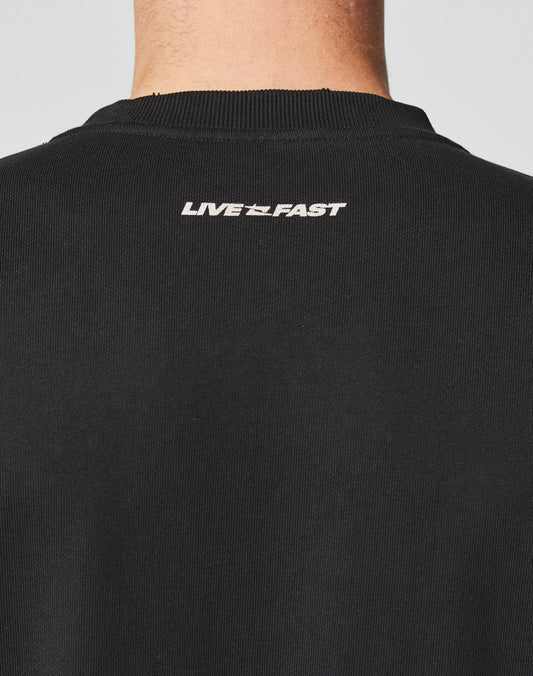 The back of the LFDY Mystic Sweater by LIVE FAST DIE YOUNG, featuring black ribbed cotton and “LIVE FAST” in white near the neckline. The clean topstitching is visible above the wearer’s neck and partial head.
