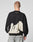 A person with short hair, seen from behind, wears the LFDY Mystic Sweater by LIVE FAST DIE YOUNG—black with white abstract patterns and LIVE FAST text on the upper back—paired with light gray Oversize Fit jeans against a plain background.