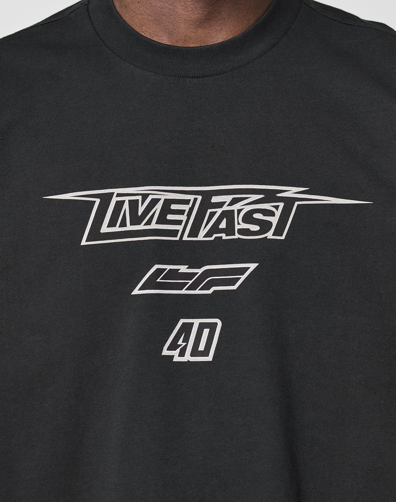 A close-up of the LFDY Triple Racing Tee by LIVE FAST DIE YOUNG—a black, 100% Baumwolle oversized shirt with multilogo front print, bold white LIVE FAST lettering, LF symbols, and the number 40 for ultimate comfort.