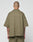 A person with a shaved head is seen from behind wearing an olive green LIVE FAST DIE YOUNG Basic Knit Shirt, an oversize ribbed short-sleeve top with Hemdkragen and Brusttasche. Their tattooed arms stand out against a plain light background.