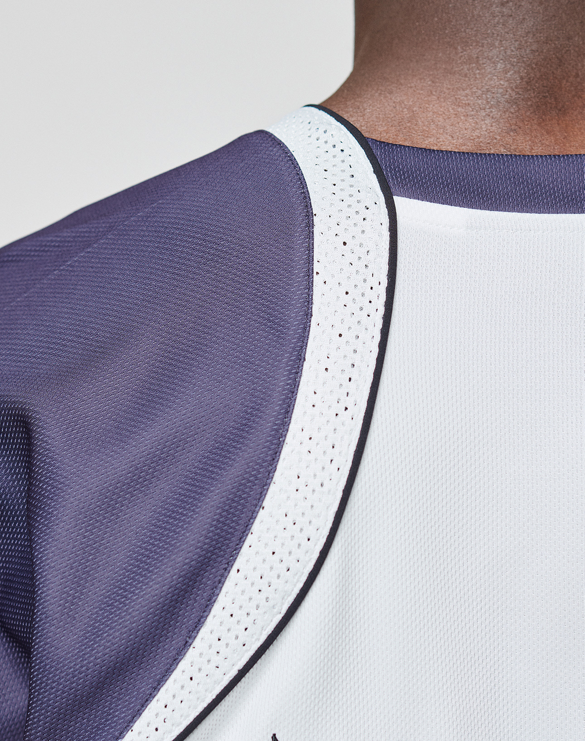 Close-up of a person wearing the LFDY Call Us Jersey by LIVE FAST DIE YOUNG, featuring dark purple and white polyester mesh, black trim, and a V-Ausschnitt neckline. The oversize fit emphasizes the unique texture and stitching details.