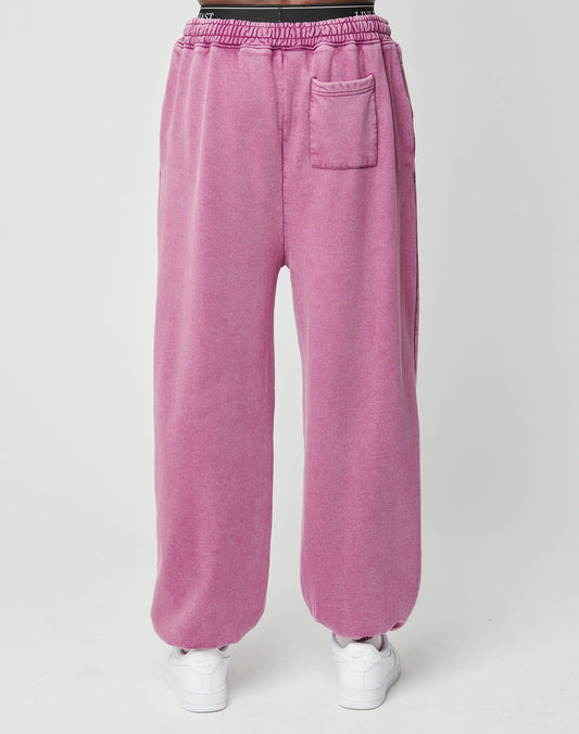 A person wears the Loyal Loose Jogger by LIVE FAST DIE YOUNG—pink, high-waisted, oversize-fit sweatpants with an elastic waistband and small front pocket—paired with white sneakers against a plain white background.