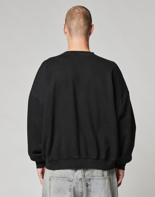 A person with a shaved head faces away from the camera, wearing a LIVE FAST DIE YOUNG LFDY Hardwear Sweater in black and faded light blue jeans, set against a plain gray background.