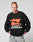 A person with short hair wears the black LFDY Hardwear Sweater by LIVE FAST DIE YOUNG, featuring an orange Pufferprint graphic and white LIVE FAST HARDWEAR text, standing with hands in light blue jean pockets against a plain background.