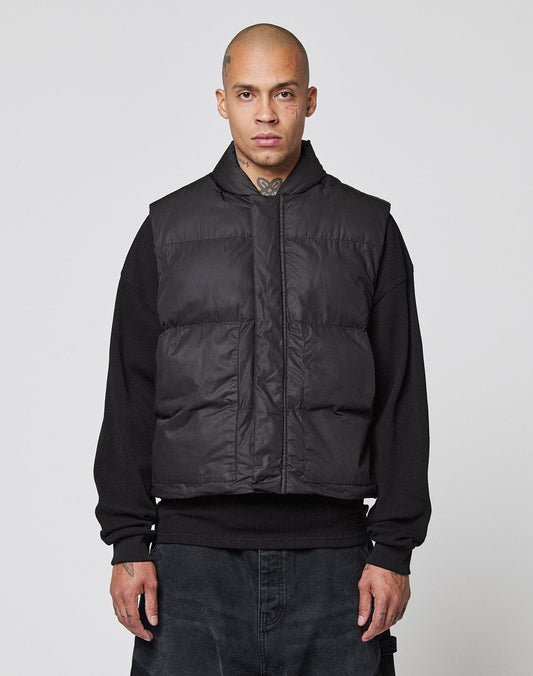 A person with a shaved head wears the LIVE FAST DIE YOUNG Basic Cropped Vest with große Taschen over a black sweatshirt and dark pants, standing facing forward against a plain light gray background.