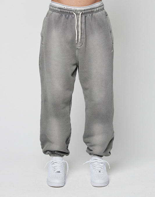 A person models the LIVE FAST DIE YOUNG Basic Loose Jogger—light gray with a subtle logo and elastic waistband—paired with white sneakers, standing against a plain light gray background.