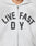 A person wears the Live Fast Rivet Hooded Zip by LIVE FAST DIE YOUNG—a light gray, oversized zip-up hoodie featuring bold black and white LIVE FAST D Y lettering across the chest. Only their lower face and upper torso are shown.