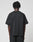 A person with short, twisted hair is seen from behind, wearing the oversize fit LIVE FAST DIE YOUNG Basic +49 Tee, made of 100% Baumwolle, and black pants against a plain white background.