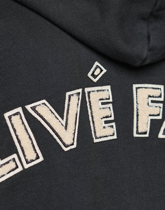 Close-up of the black LFDY LÉquipe Hooded Zip by LIVE FAST DIE YOUNG, showing raised stitched white letters and bold chenille stick-outlined embroidery for standout texture.