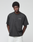 A man with short curly hair wears the LFDY Grand Theft Tee by LIVE FAST DIE YOUNG, a black 100% Baumwolle oversized T-shirt with LIVE FAST front and back print, paired with light-colored pants against a light gray background.