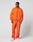 A man stands against a plain background in the LIVE FAST DIE YOUNG Live Fast Trackjacket, a bright orange nylon-elastane zip-up and matching pants with elastic cuffs, paired with white sneakers. He looks to his left with relaxed confidence.