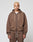 A person with short blond hair wears the LIVE FAST DIE YOUNG LFDY Lightweight Hooded Zip in brown, paired with matching pants, standing against a plain light gray background and looking directly at the camera with a neutral expression.