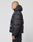 A person with a shaved head wears the LIVE FAST DIE YOUNG Live Fast Puffer Jacket in oversize fit black with a hood, featuring a small logo on the left sleeve and a reflective print on the side, standing in profile against a white background.