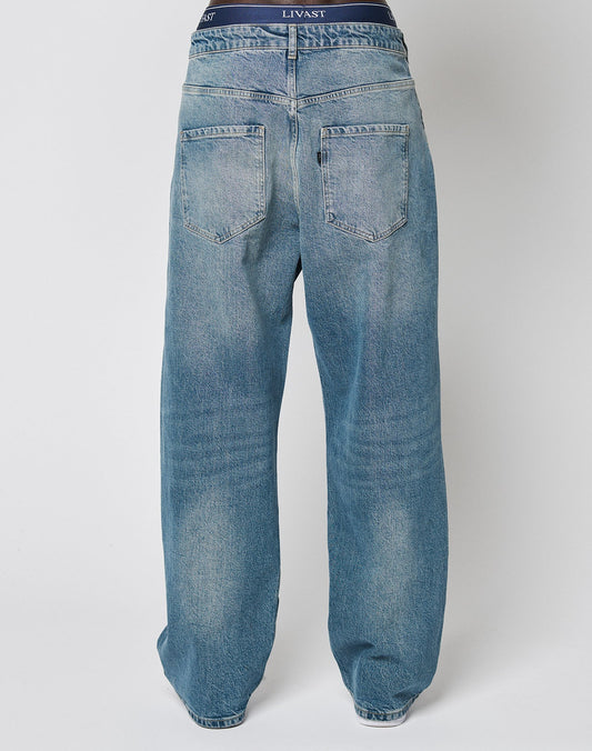 Back view of LFDY Tire Tracks Denim by LIVE FAST DIE YOUNG, featuring a baggy fit, faded blue wash, large back pockets, and visible navy waistband underwear with “LIVAST” in white. Made from 100% Baumwolle for comfort and style.
