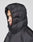 A person wears the LIVE FAST DIE YOUNG Live Fast Puffer Jacket in black, shown in profile with the hood up against a light gray background. The jacket has an oversize fit for added comfort.