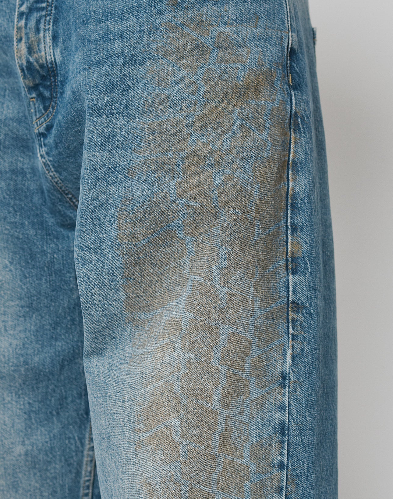 Close-up of the LFDY Tire Tracks Denim by LIVE FAST DIE YOUNG, featuring a faded, brownish Reifenabdruck stain along the side seam. Crafted from 100% cotton for comfort in a relaxed baggy fit.