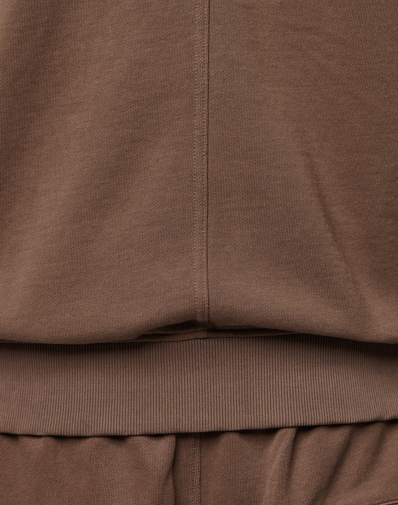 Close-up of brown fabric clothing, showing the seam and waistband detail, likely part of the LFDY Lightweight Hooded Zip by LIVE FAST DIE YOUNG. The 100% Baumwolle texture and precise stitching are clearly visible.