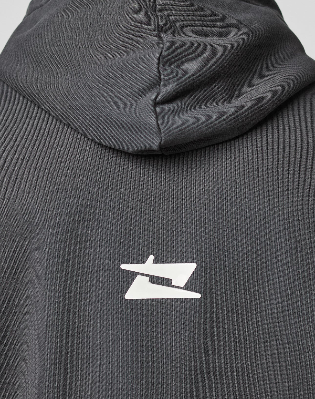 A close-up of the back of the dark gray LIVE FAST DIE YOUNG LFDY Core Hooded in Oversize Fit, featuring a white stylized geometric logo printed below the hood.