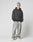 A person in a gray beanie, LIVE FAST DIE YOUNG LFDY Core Hooded black hoodie with Logo-Stick, light baggy Oversize Fit jeans aus Baumwolle, and white sneakers stands hands-in-pockets against a plain light background.