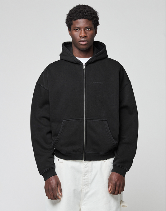 A person stands facing forward, wearing a LIVE FAST DIE YOUNG LFDY Grand Theft Hooded Zip in black and white pants, against a plain light gray background.