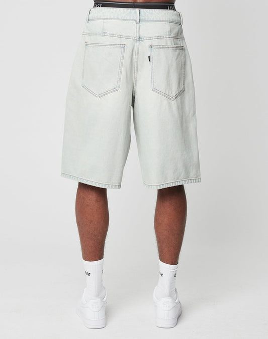 Someone is shown from the back wearing LIVE FAST DIE YOUNG LFDY Jorts—light-wash, knee-length denim shorts with a Gesäßtasche—paired with white socks and sneakers, standing against a plain white background.