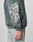 A person is seen from the side wearing the LFDY Window Hooded by LIVE FAST DIE YOUNG, a green-gray oversized sweatshirt with a white sleeve graphic and made from 100% Baumwolle, styled with light-wash jeans. Only part of the body is visible.