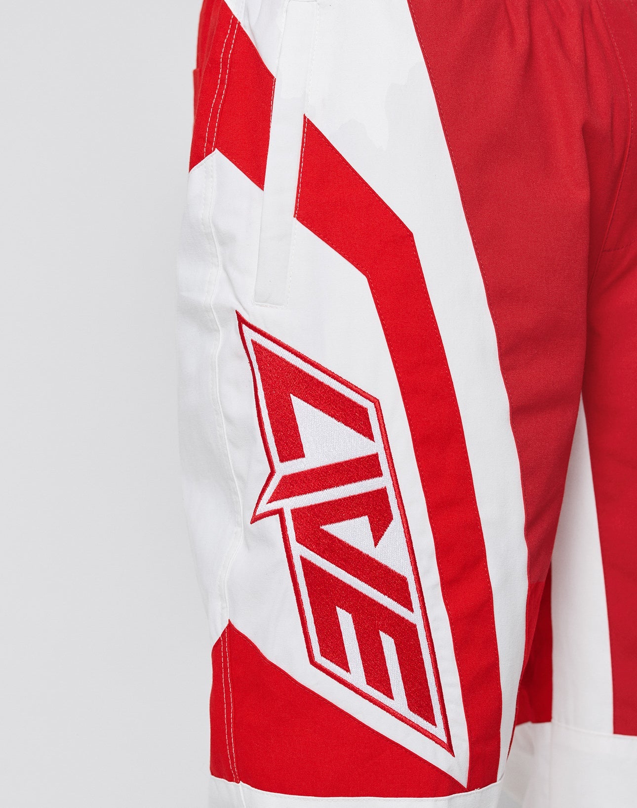 The LFDY Cross Pants by LIVE FAST DIE YOUNG feature red and white bold angular patterns, LIVE lettering on the side, Stick Applikationen, an oversize fit, and sporty fabric shown in a close-up of the left leg.