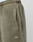 Close-up of the LIVE FAST DIE YOUNG Basic Loose Jogger in olive green, featuring a handmade fade effect, zippered side pocket, white LFDY logo near the pocket, loose fit, and elastic waistband. A white shirt is visible at the top.
