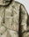 A close-up of the LIVE FAST DIE YOUNG Live Fast Nylon Jacket, featuring green and beige digital camouflage, an oversize fit, elastic hood drawstring, and “LIVE FAST™” printed in white on the chest.