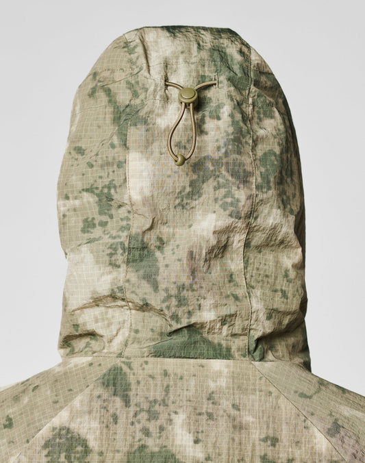 A close-up of the back of the LIVE FAST DIE YOUNG Live Fast Nylon Jacket in an oversize fit with green and beige camouflage, a hood with elastic drawstring and plastic toggle, and grid-textured fabric.