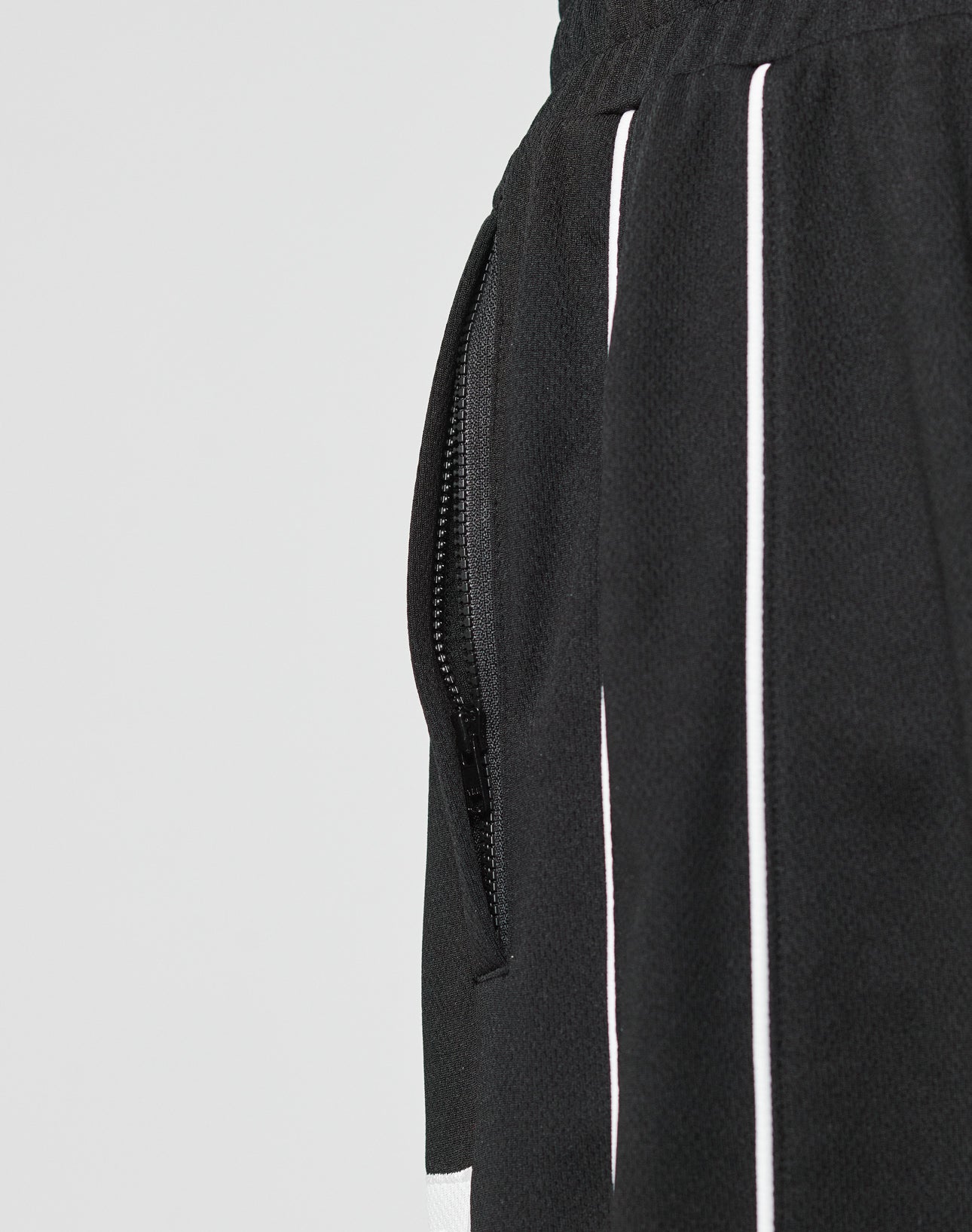 Close-up of the LFDY 55 Trackpants by LIVE FAST DIE YOUNG, featuring a side pocket with a black zipper, white vertical stripes, an elastic waistband for comfort, and a wide fit design made from durable polyester.