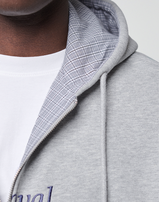Close-up of someone in a light gray LIVE FAST DIE YOUNG Flannel Lined Hooded Jacket, showing part of their face, neck, and upper chest; the hood is lined with blue flannel and worn over a white shirt.