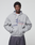 A young man with short curly hair wears a LIVE FAST DIE YOUNG Flannel Lined Hooded Jacket with printed text and graphics, standing with his hands in his pockets against a plain light gray background.